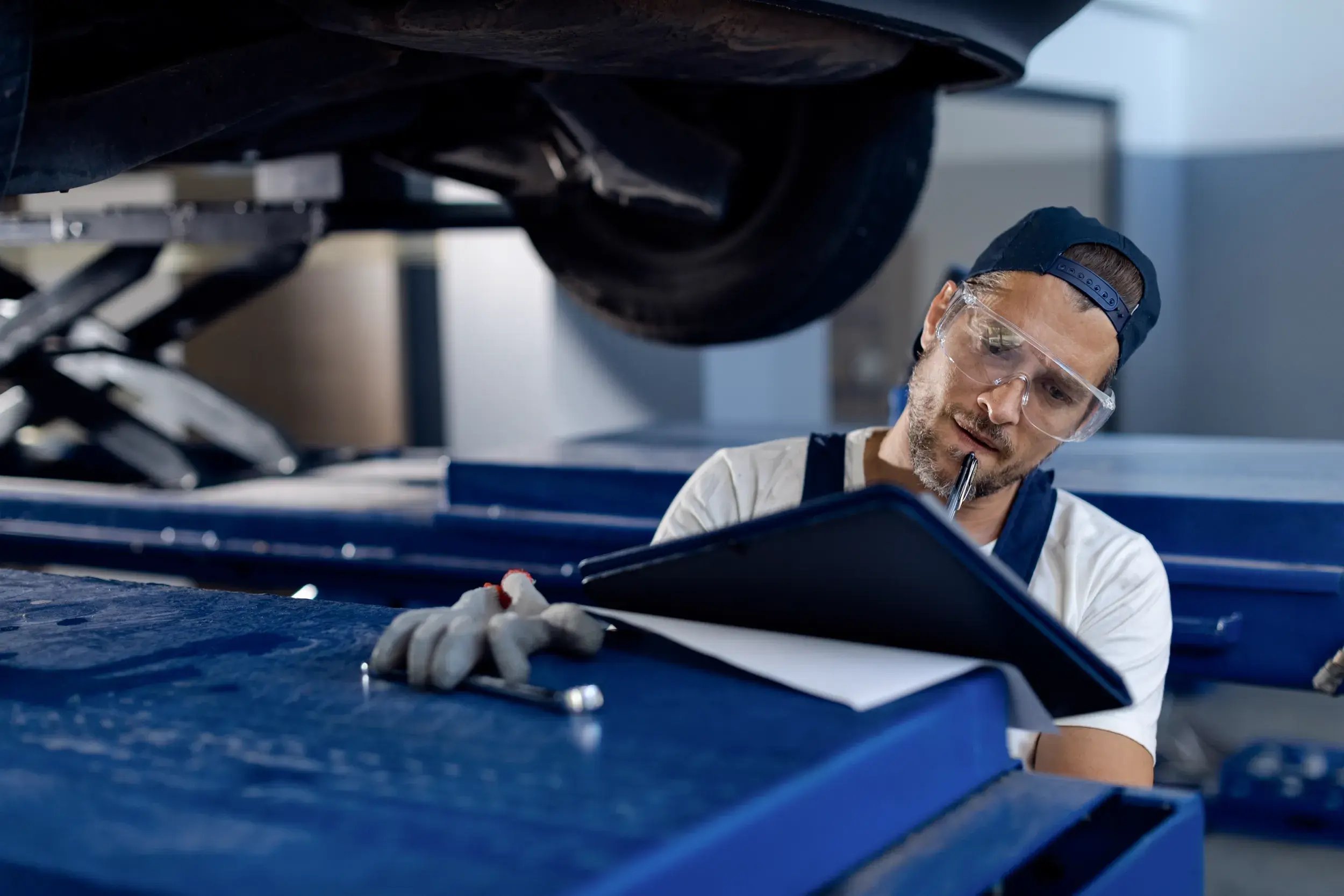 auto-repairman-taking-notes-while-examining-vehicle-workshop